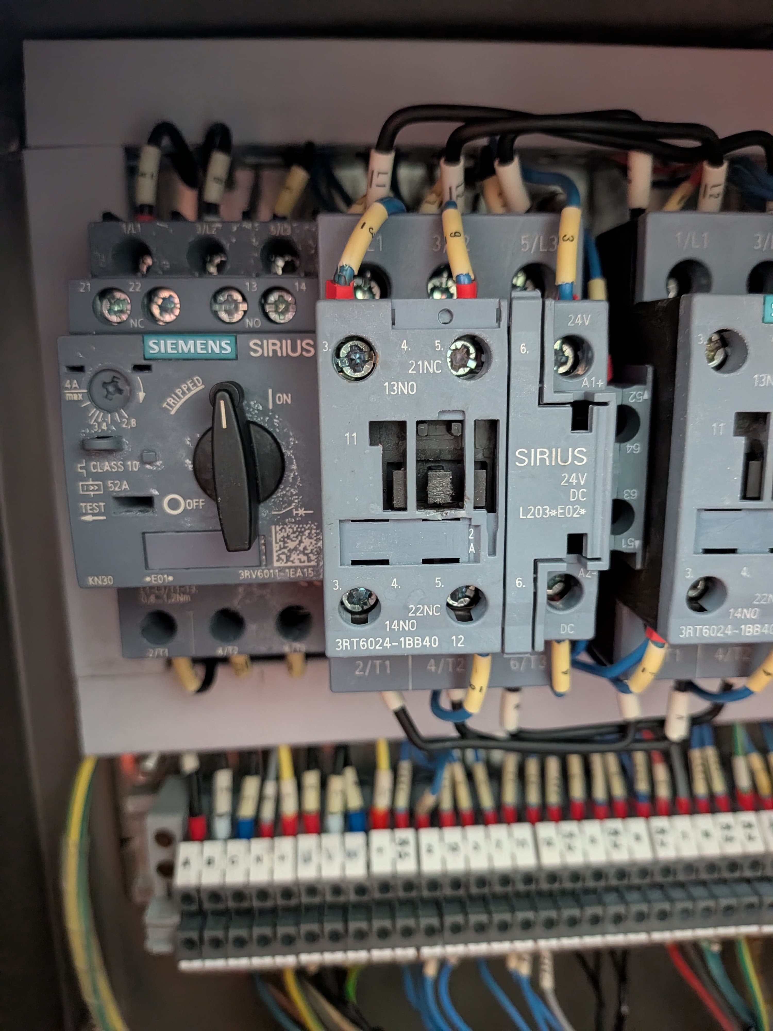 Contactors and relays mounted on a DIN rail in a control panel